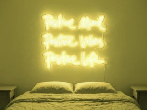Neonskylt «Positive Mind, Vibes, Life» i gul LED-neon, monterad på vägg