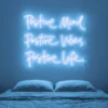 Neonskylt «Positive Mind, Vibes, Life» i isblå LED-neon, monterad på vägg