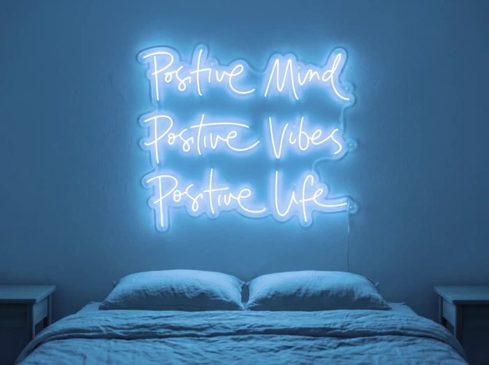 Neonskylt «Positive Mind, Vibes, Life» i isblå LED-neon, monterad på vägg