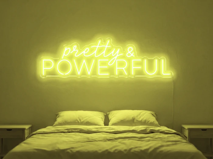 Neonskylt «Pretty And Powerful» i gul LED-neon, monterad på vägg