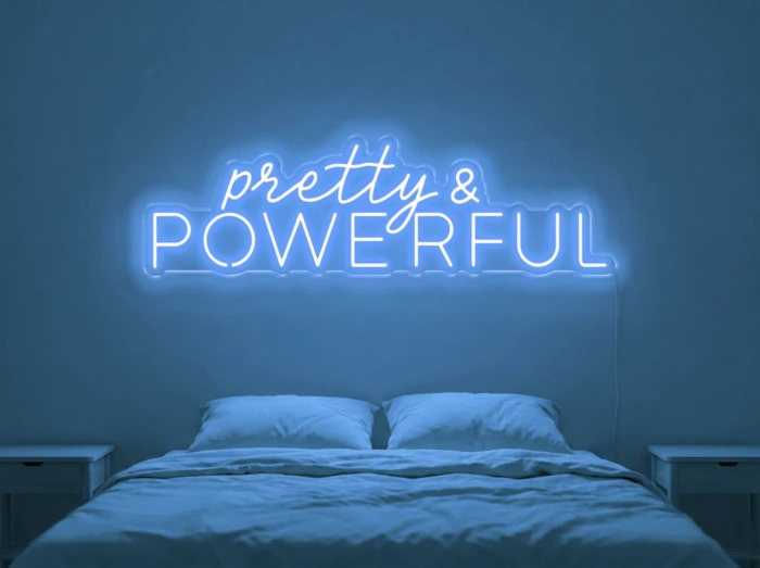 Neonskylt «Pretty And Powerful» i isblå LED-neon, monterad på vägg