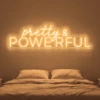 Neonskylt «Pretty And Powerful» i orange LED-neon, monterad på vägg