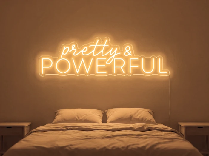 Neonskylt «Pretty And Powerful» i orange LED-neon, monterad på vägg