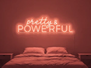 Neonskylt «Pretty And Powerful» i röd LED-neon, monterad på vägg