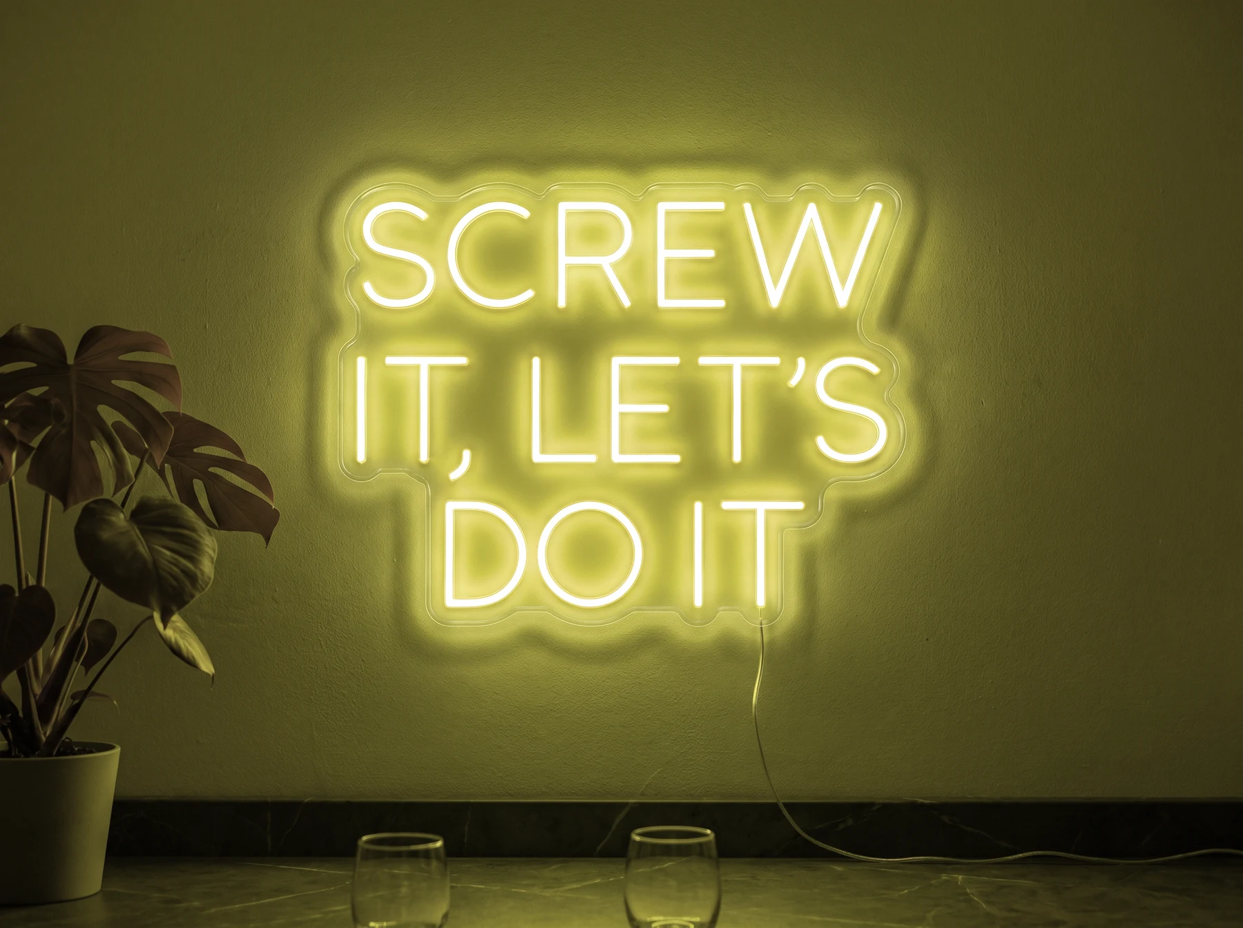 Neonskylt «Screw It Let’s Do It» i gul LED-neon, monterad på vägg