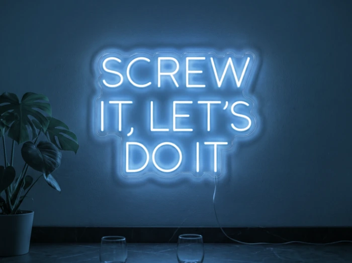 Neonskylt «Screw It Let’s Do It» i isblå LED-neon, monterad på vägg