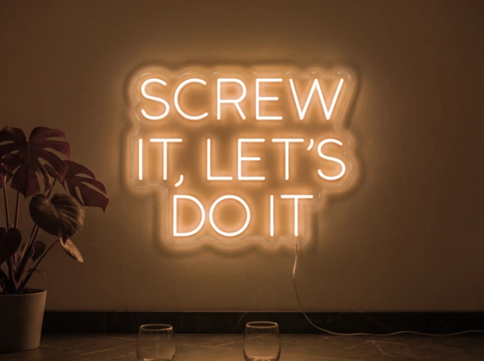 Neonskylt «Screw It Let’s Do It» i orange LED-neon, monterad på vägg