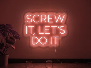Neonskylt «Screw It Let’s Do It» i röd LED-neon, monterad på vägg