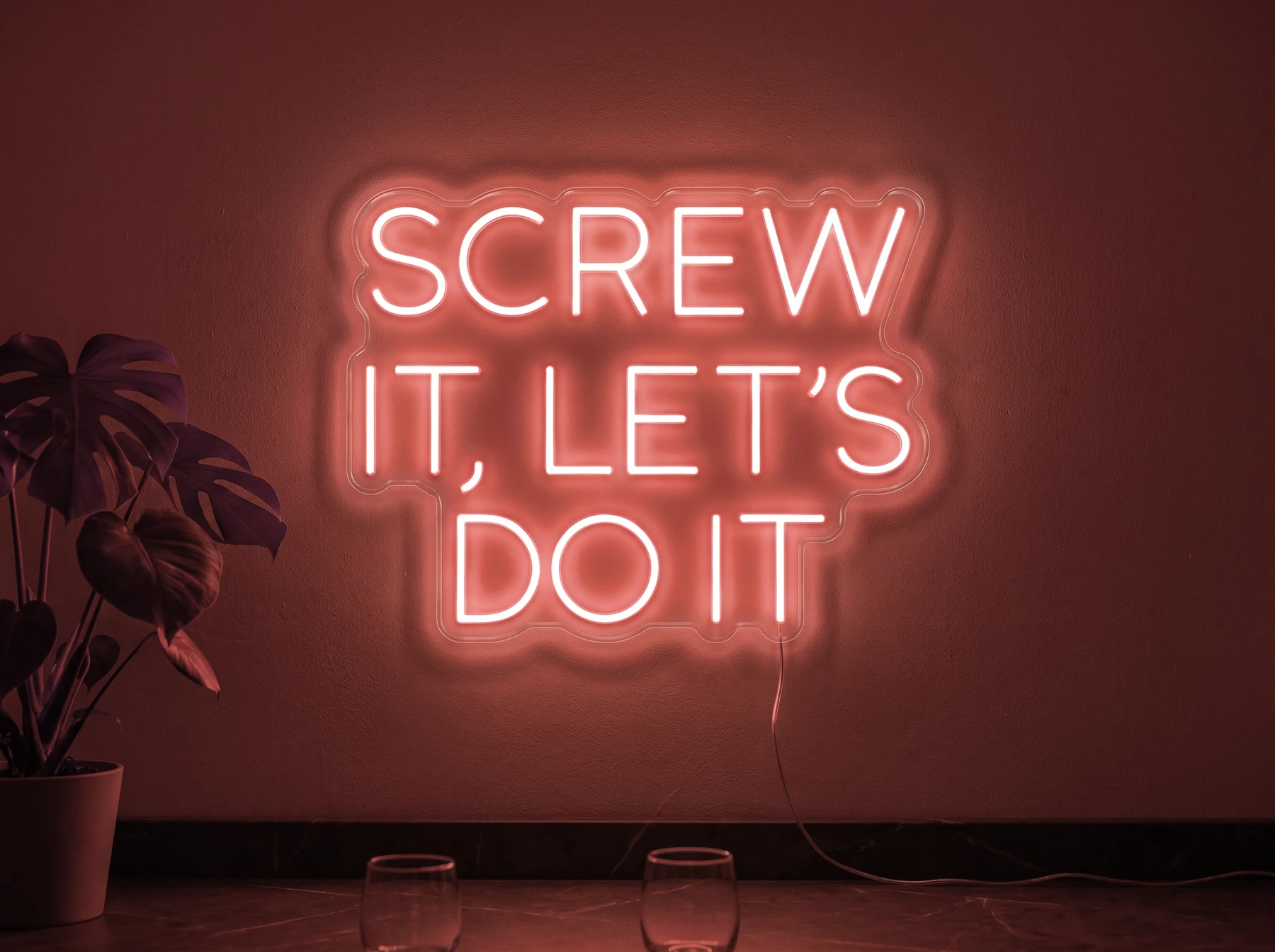 Neonskylt «Screw It Let’s Do It» i röd LED-neon, monterad på vägg