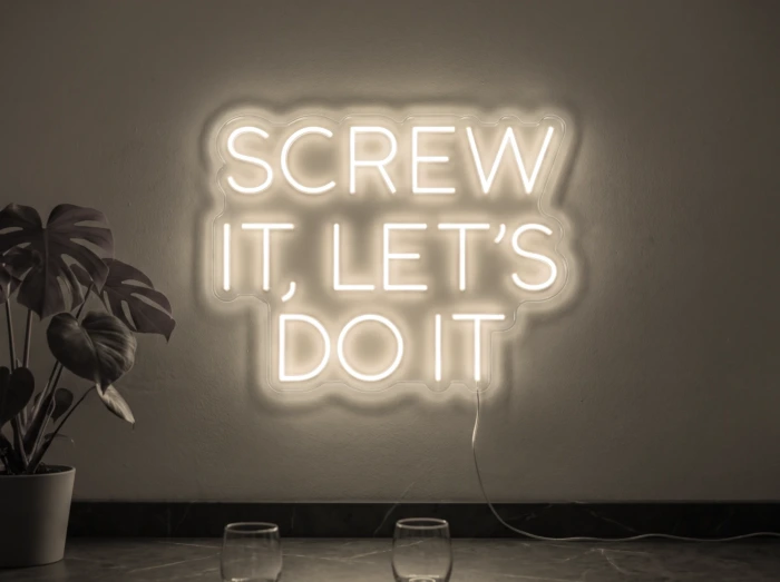 Neonskylt «Screw It Let’s Do It» i varmvit LED-neon, monterad på vägg
