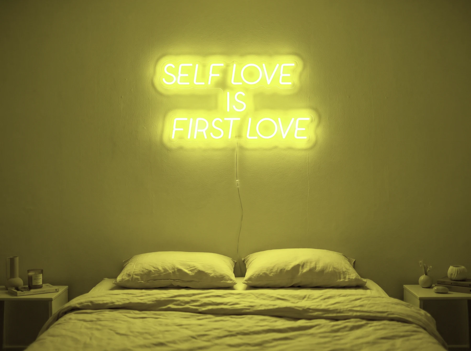 Neonskylt «Self Love Is First Love» i gul LED-neon, monterad på vägg