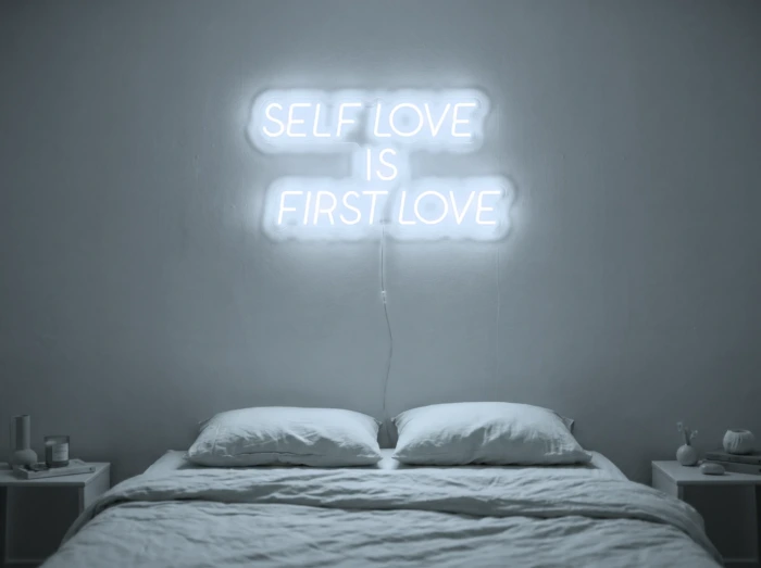 Neonskylt «Self Love Is First Love» i iskall vit LED-neon, monterad på vägg