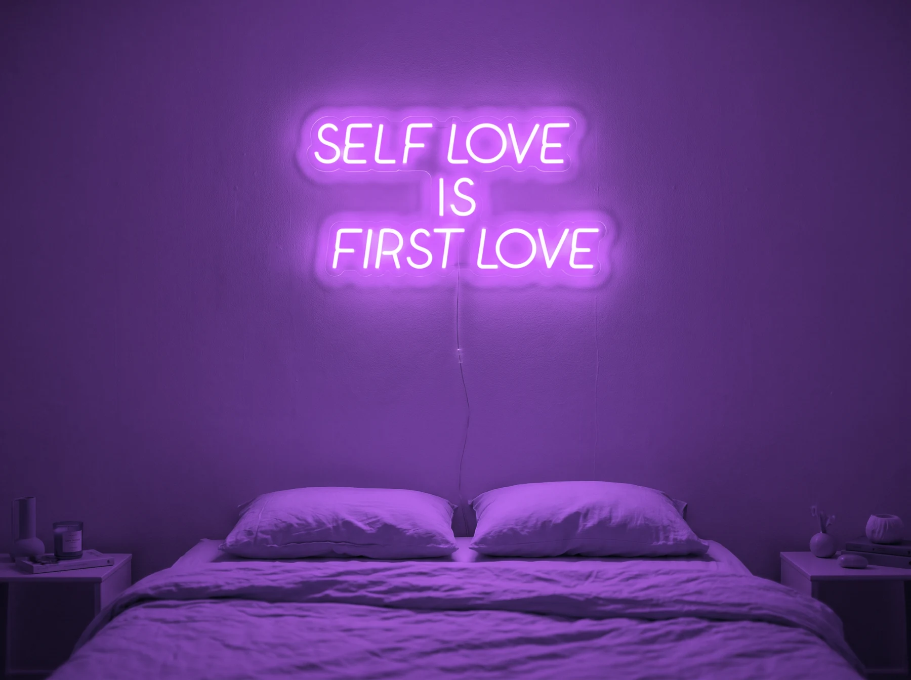 Neonskylt «Self Love Is First Love» i lila LED-neon, monterad på vägg