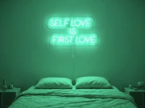 Neonskylt «Self Love Is First Love» i mintgrön LED-neon, monterad på vägg