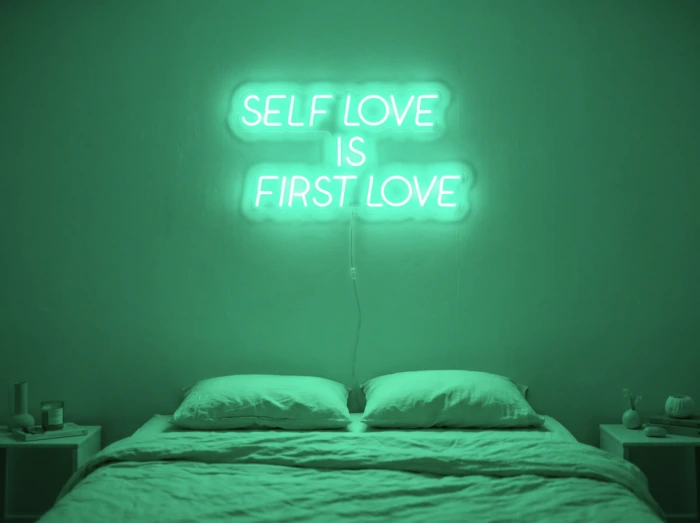Neonskylt «Self Love Is First Love» i mintgrön LED-neon, monterad på vägg