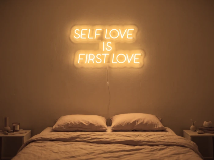 Neonskylt «Self Love Is First Love» i orange LED-neon, monterad på vägg