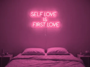 Neonskylt «Self Love Is First Love» i rosa LED-neon, monterad på vägg