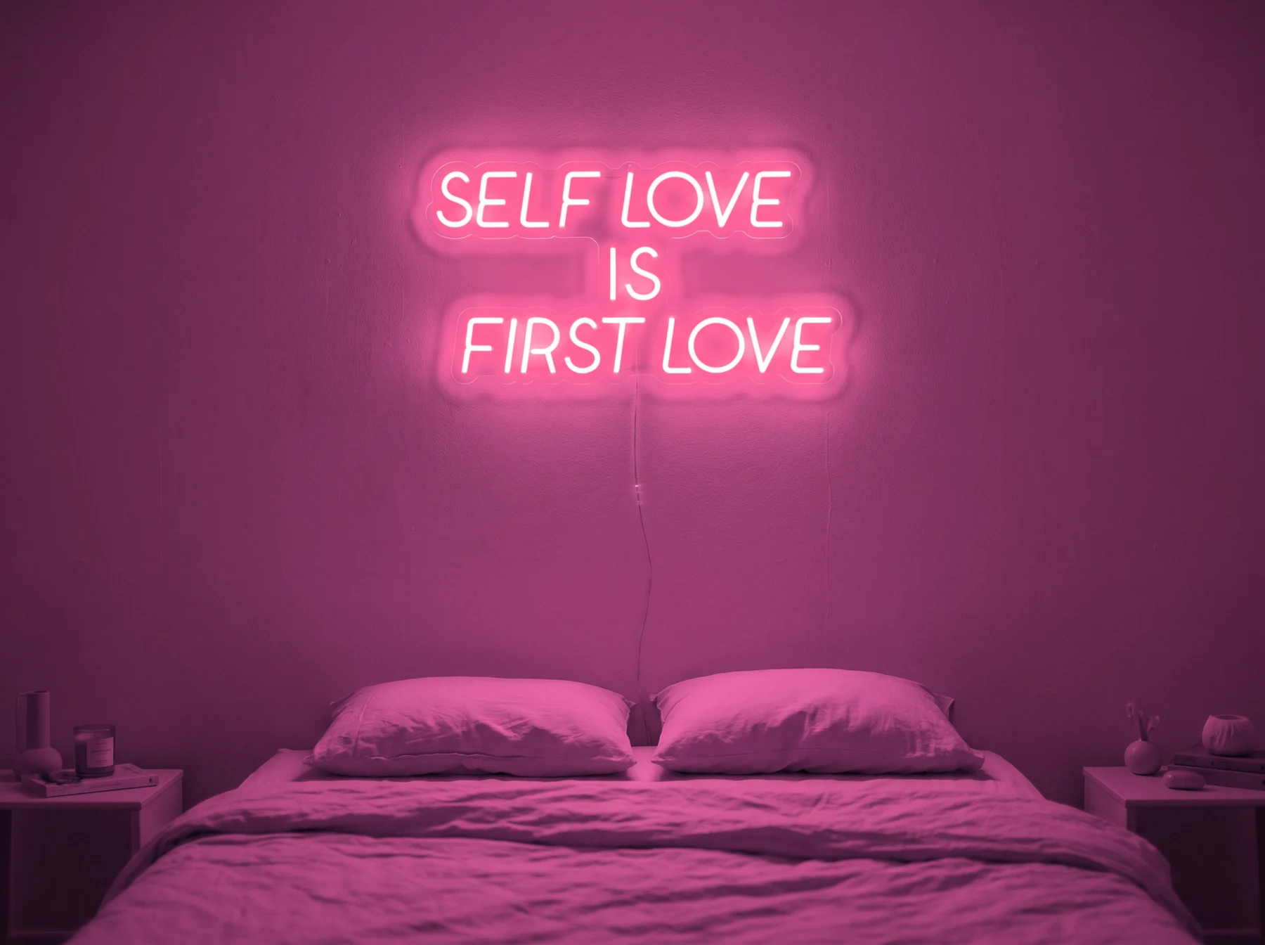 Neonskylt «Self Love Is First Love» i rosa LED-neon, monterad på vägg