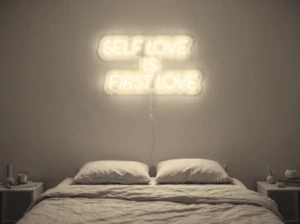Neonskylt «Self Love Is First Love» i varmvit LED-neon, monterad på vägg