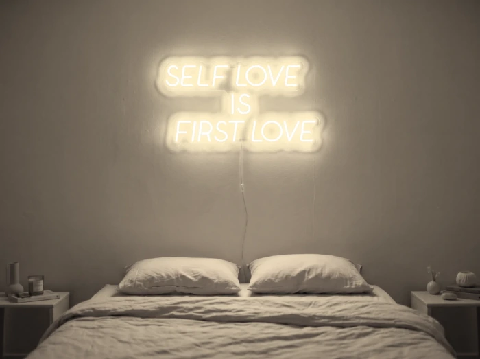 Neonskylt «Self Love Is First Love» i varmvit LED-neon, monterad på vägg