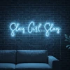 Neonskylt «Slay Girl Slay» i isblå LED-neon, monterad på vägg