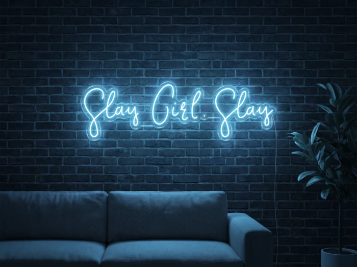 Neonskylt «Slay Girl Slay» i isblå LED-neon, monterad på vägg