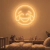 Neonskylt «Smiley» i orange LED-neon, monterad på vägg
