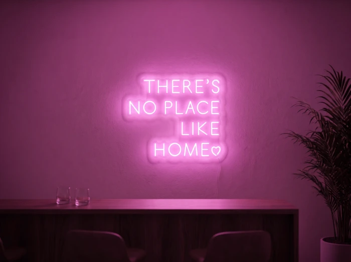 Neonskylt «There’s No Place Like Home, versaler» i rosa LED-neon, monterad på vägg