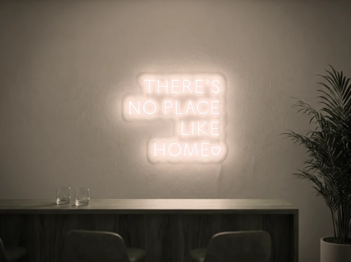 Neonskylt «There’s No Place Like Home, versaler» i varmvit LED-neon, monterad på vägg
