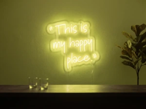 Neonskylt «This Is My Happy Place» i gul LED-neon, monterad på vägg