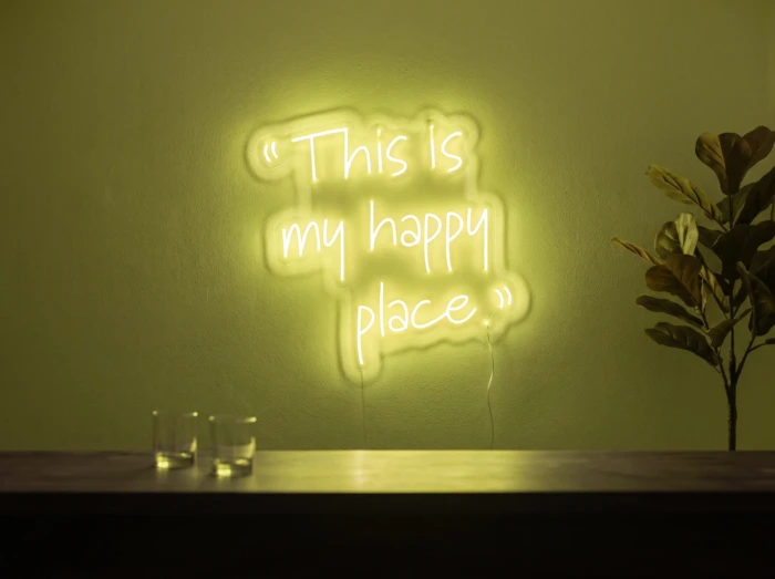 Neonskylt «This Is My Happy Place» i gul LED-neon, monterad på vägg