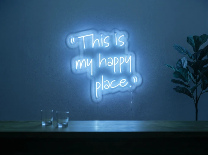 Neonskylt «This Is My Happy Place» i isblå LED-neon, monterad på vägg