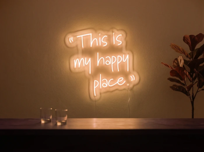Neonskylt «This Is My Happy Place» i orange LED-neon, monterad på vägg