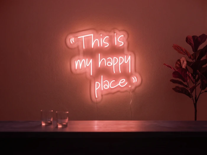 Neonskylt «This Is My Happy Place» i röd LED-neon, monterad på vägg