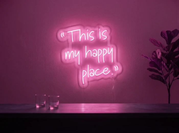 Neonskylt «This Is My Happy Place» i rosa LED-neon, monterad på vägg