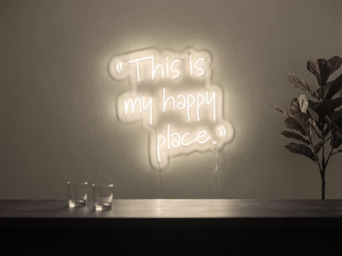 Neonskylt «This Is My Happy Place» i varmvit LED-neon, monterad på vägg