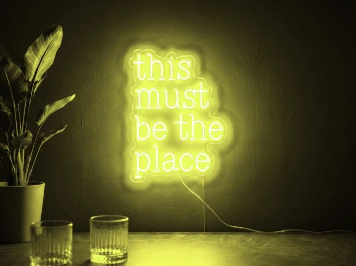 Neonskylt «This Must Be The Place» i gul LED-neon, monterad på vägg