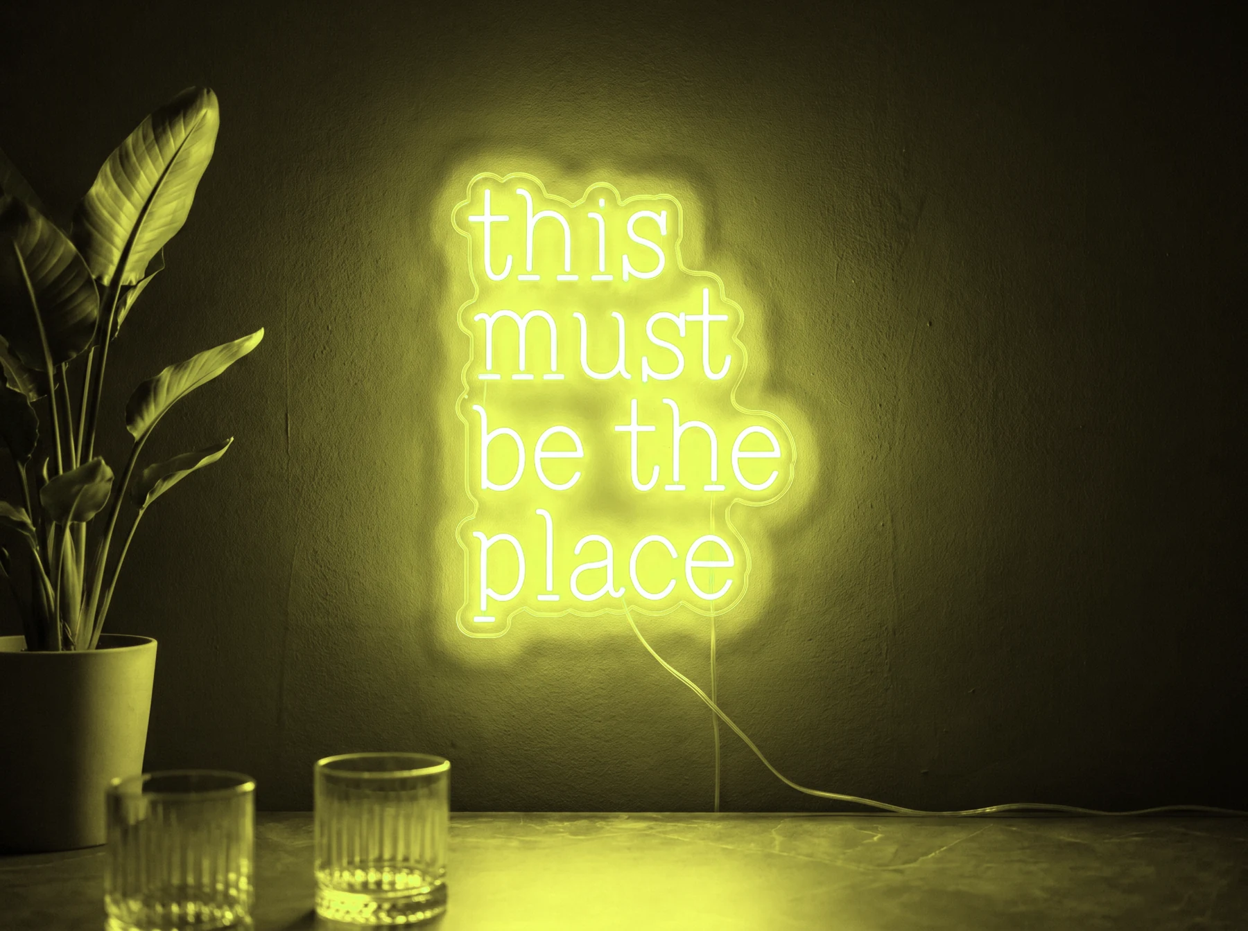 Neonskylt «This Must Be The Place» i gul LED-neon, monterad på vägg