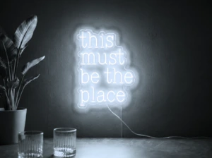 Neonskylt «This Must Be The Place» i iskall vit LED-neon, monterad på vägg