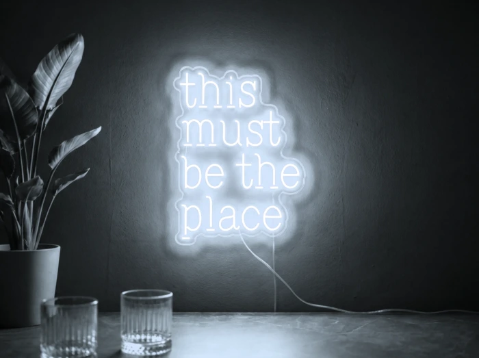 Neonskylt «This Must Be The Place» i iskall vit LED-neon, monterad på vägg