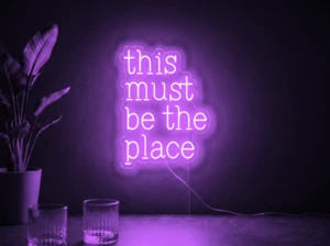 Neonskylt «This Must Be The Place» i lila LED-neon, monterad på vägg