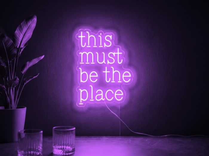 Neonskylt «This Must Be The Place» i lila LED-neon, monterad på vägg