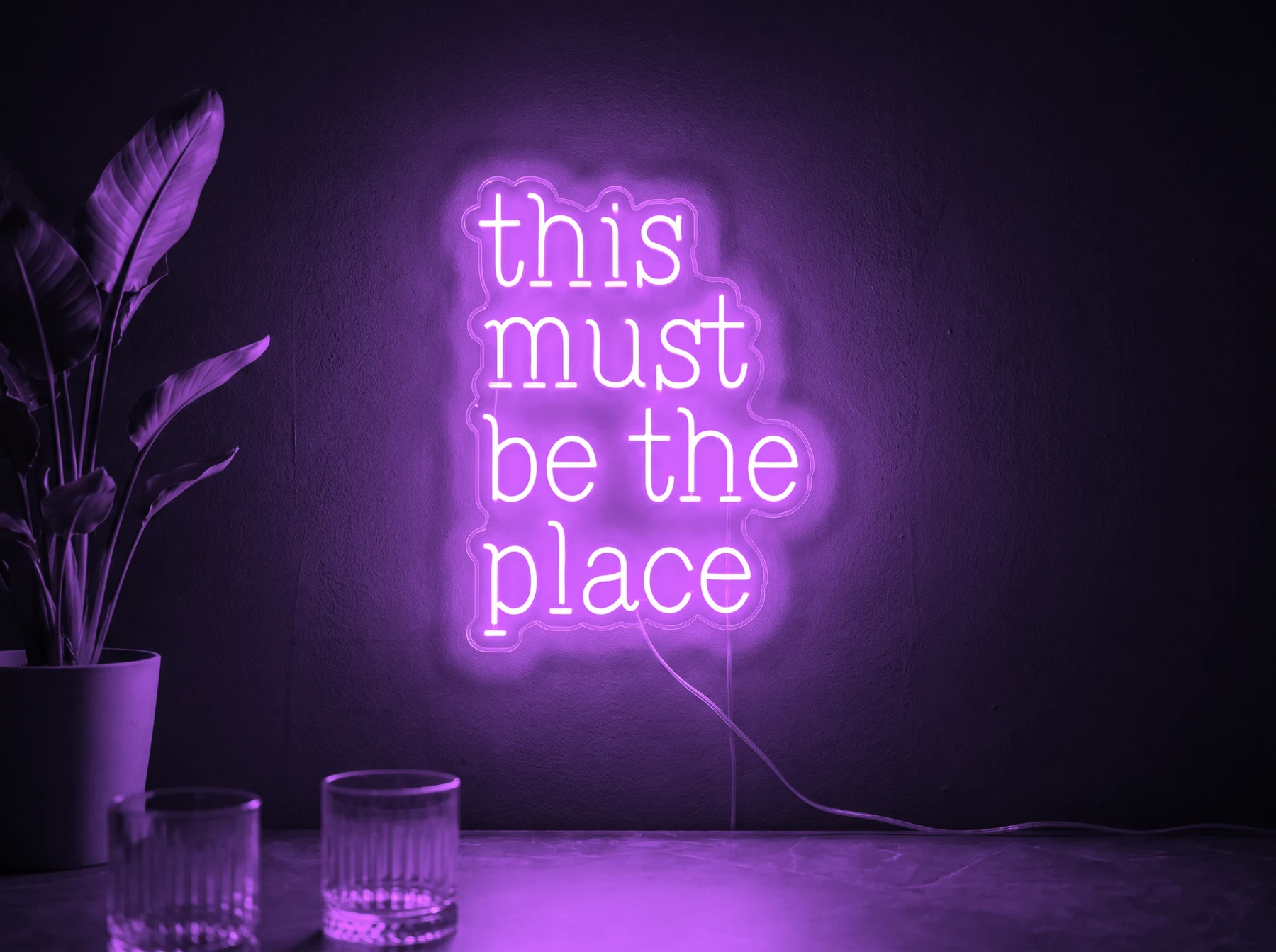 Neonskylt «This Must Be The Place» i lila LED-neon, monterad på vägg