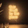 Neonskylt «This Must Be The Place» i orange LED-neon, monterad på vägg