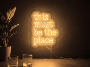 Neonskylt «This Must Be The Place» i orange LED-neon, monterad på vägg