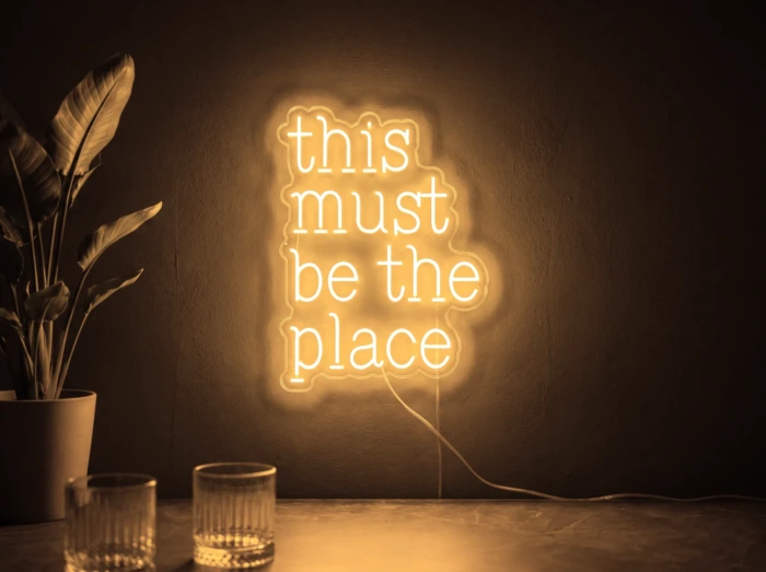 Neonskylt «This Must Be The Place» i orange LED-neon, monterad på vägg