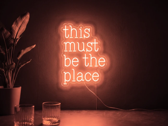 Neonskylt «This Must Be The Place» i röd LED-neon, monterad på vägg