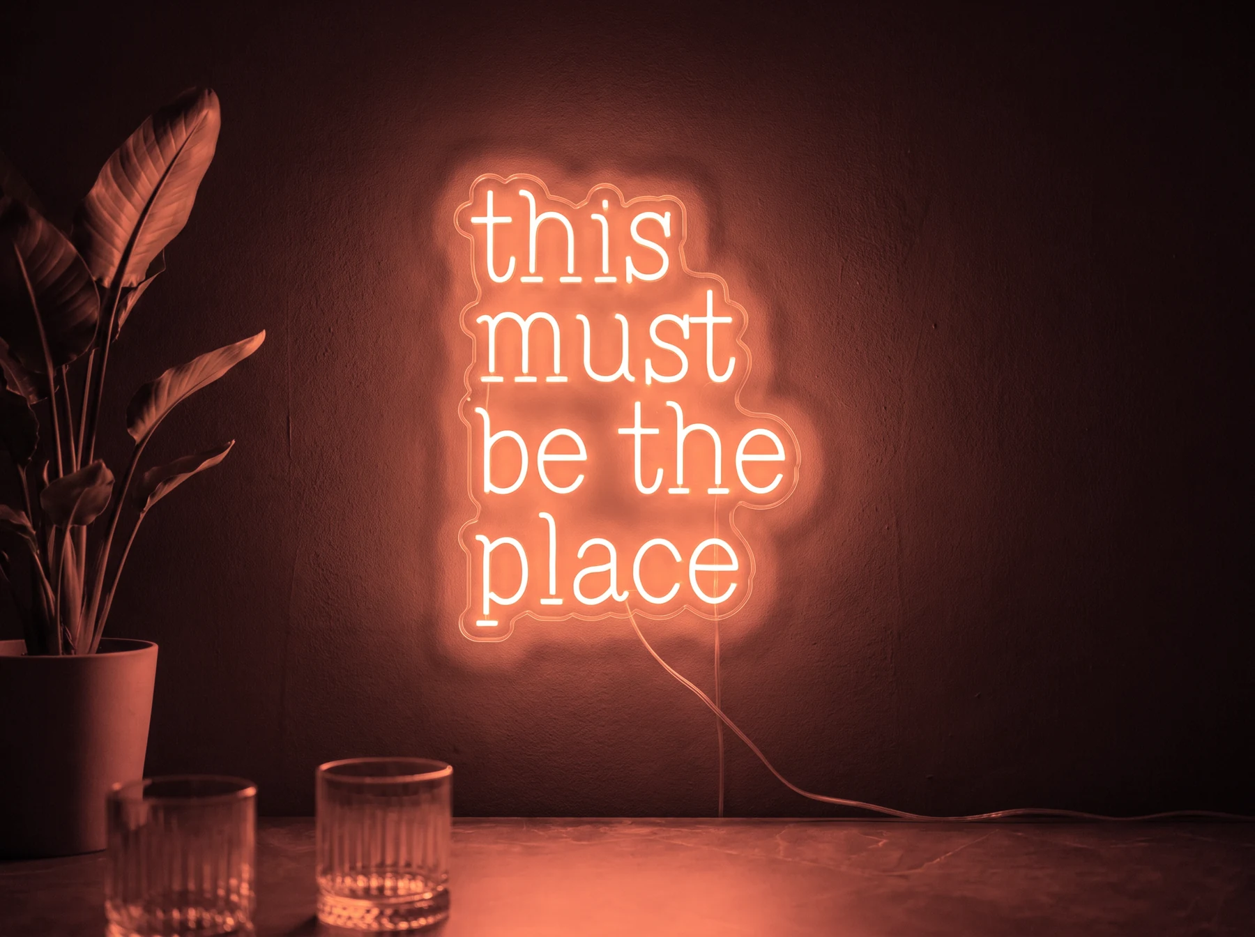 Neonskylt «This Must Be The Place» i röd LED-neon, monterad på vägg