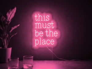 Neonskylt «This Must Be The Place» i rosa LED-neon, monterad på vägg