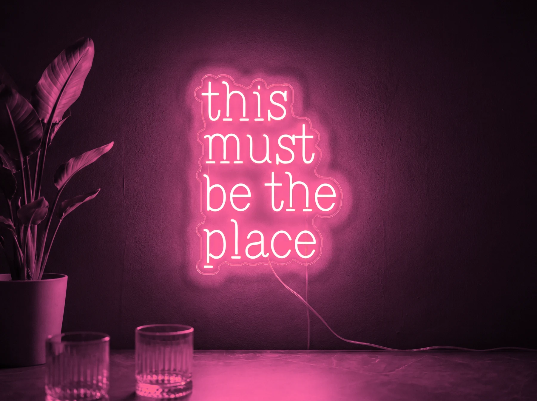 Neonskylt «This Must Be The Place» i rosa LED-neon, monterad på vägg